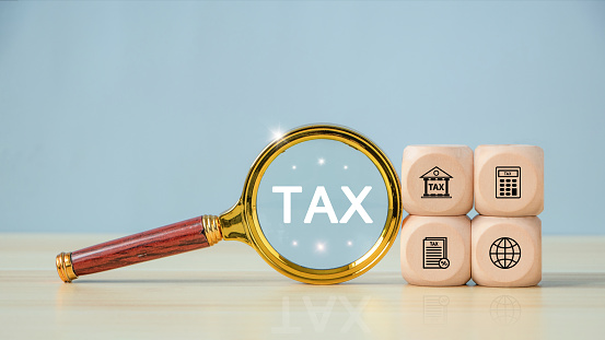 TAX text on Magnifying glass with tax icon in the wooden cube for income tax return and submit tax for payment tax documents online to the government. state taxes.financial research. report. VAT