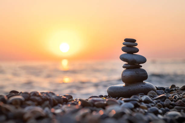 istock Stack of balanced rocks on beach during sunset, golden hour on the beach 1691784901