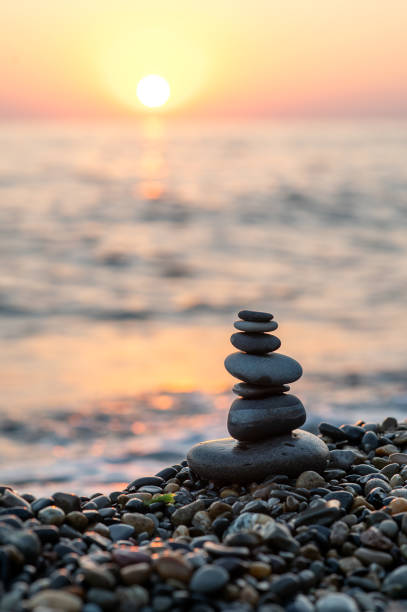 istock Stack of balanced stones on the beach during sunset, golden hour on the beach. Vertical photo 1691785475