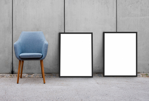 chair and blank picture frames on sidewal with concrete wall background