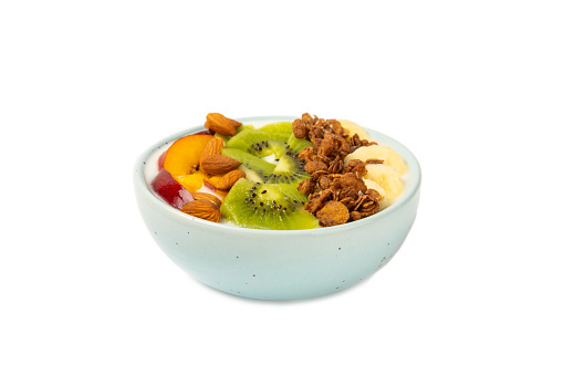 Bowl of granola with yogurt and fresh almonds, blueberries, raspberries,peach and strawberries isolated on white background. Healthy food. balanced breakfast.