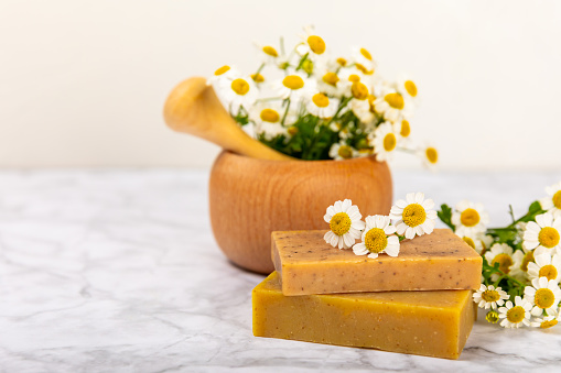 Natural homemade soap with chamomile flowers on  background. Spa procedure. Beauty concept. Body skin care. Place for text. copy space.