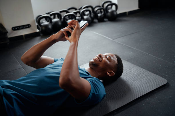 istock Young black man typing on mobile phone while resting at the gym 1691812911
