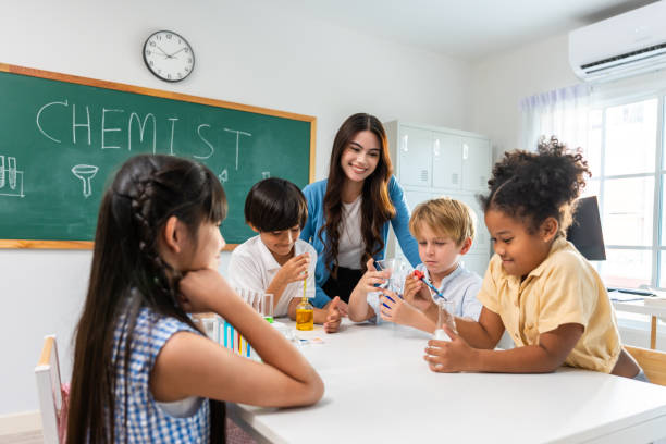 istock Adorable student learn with teacher in classroom at elementary school. Young brilliant and smart children sit on table and study chemistry experiment with happiness and fun activity at kindergarten. 1691814073