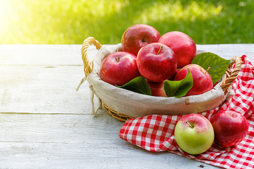 Basket with fresh red apples on the garden table with copy space