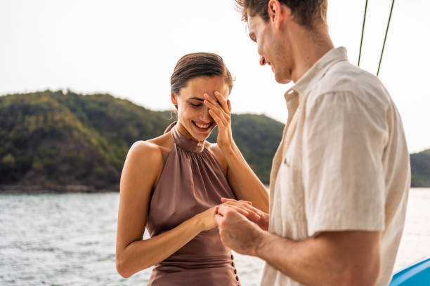 caucasian young man make surprise proposal of marriage to girlfriend. attractive romantic male proposing to beautiful happy woman with wedding ring enjoying surprise engagement while yachting together - fästfolk bildbanksfoton och bilder