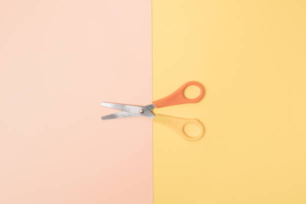istock Scissors with yellow and orange handle on pastel pink and yellow background. Minimal design. 1691840477