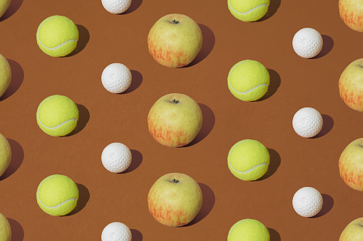 istock Tennis and golf ball with yellow apple  on a brown background. Pattern. 1691841540
