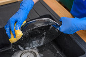 Washing greasy dishes in the sink with a sponge with plenty of foam
