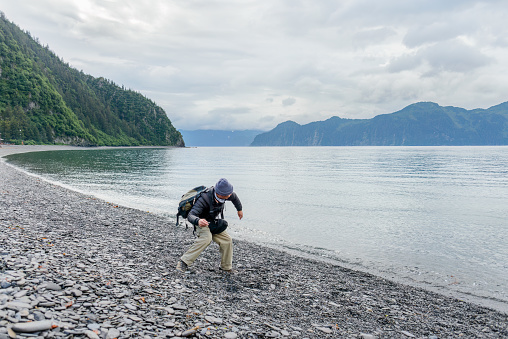 Tourist stone skipping at Fox Island at Kenai Fjords National Park. Seward. Alaska.