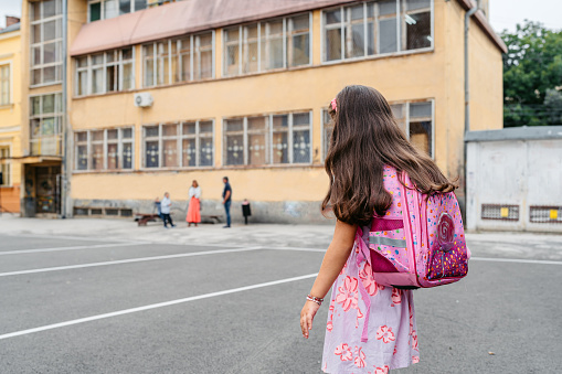 Little girl with a backpack going to school alone.