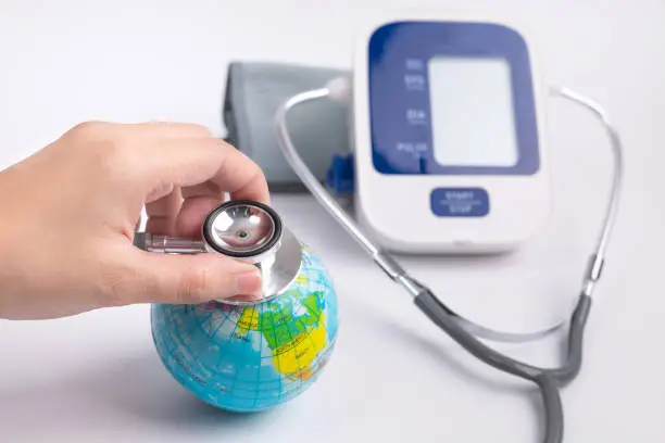 Close up man's hand used stethoscope for health check the globe earth beside digital blood-pressure meter. World environment and earth day concept. save the world concept.