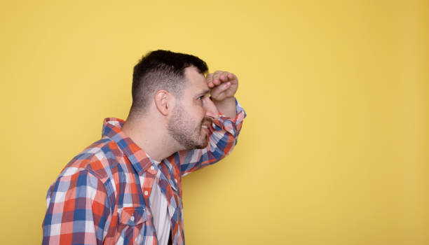 gaie homme barbu je pose isolé sur fond jaune dans le studio. concept de style de vie des gens. maquette d’espace de copie. se tenir la main sur le front en regardant au loin. - back to front fashion men male photos et images de collection