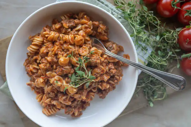 Traditional american and italian pasta dish. Ground beef in a creamy tomatoes cheese sauce. Served with fusilli noodles on a plate with decoration. Top view.