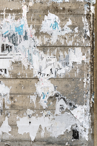 Concrete wall with colorful ripped bill posters. Grunge background