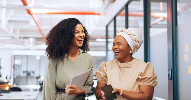 istock Black women, laughing or walking with business technology, paper or documents in modern office, coworking space or marketing company. Smile, happy or comic creative designers bonding in slow motion 1691948393