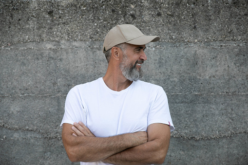 Handsome middle-aged man in casual t-shirt standing on isolated gray background