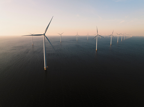 Wind turbines producing sustainable renewable energy in an offshore wind park in Flevoland, The Netehrlands. Drone point of view.