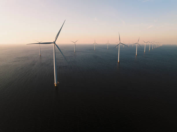 Wind turbines in an offshore wind park producing electricity during sunset stock photo