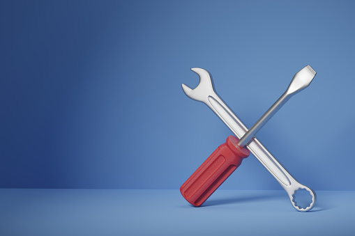 Front view of a screwdriver and a wrench crossed standing on a blue background