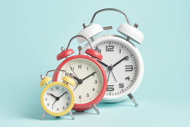 istock Three alarm clocks of different colors and sizes on a blue background. 1691977282
