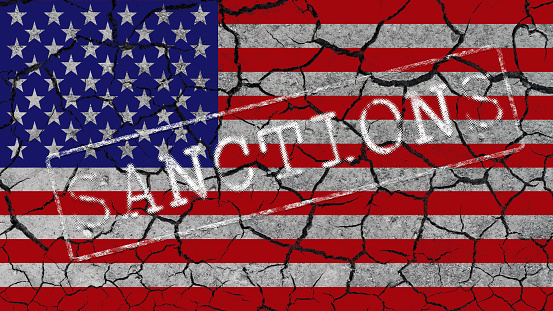 White inscription SANCTIONS on the background of the US flag and cracks