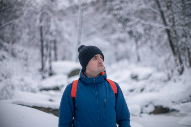 Man in winter jacket walking in snowy winter forest, snowy winter day