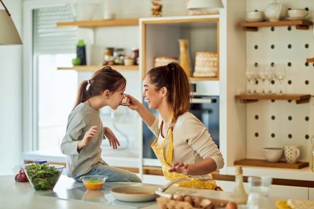 istock Mother feeding her daughter, both being in the kitchen, making lunch. 1691992072