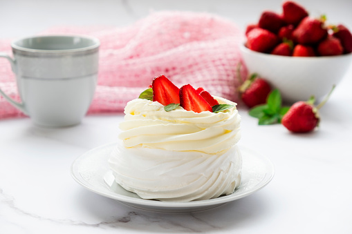 Homemade Pavlova meringue cake with fresh strawberry and whipped cream mascarpone with mint leaf decoration. Recipe of traditional dessert Anna Pavlova. Homemade pastry.