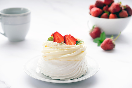 Pavlova meringue cake with fresh strawberry and whipped cream mascarpone with mint leaf decoration. Recipe of traditional dessert Anna Pavlova. Homemade pastry.