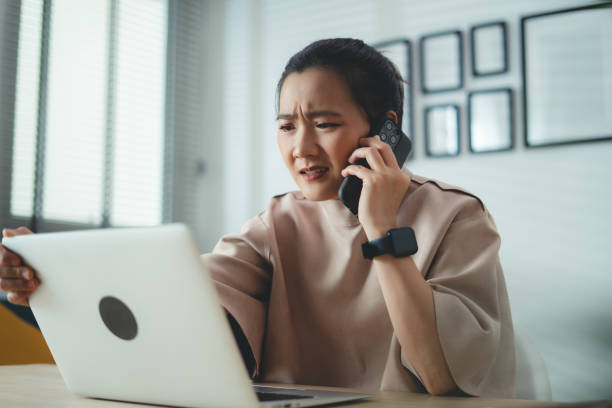 istock Asian woman using laptop and talking on smartphone about financial problem. 1691994620