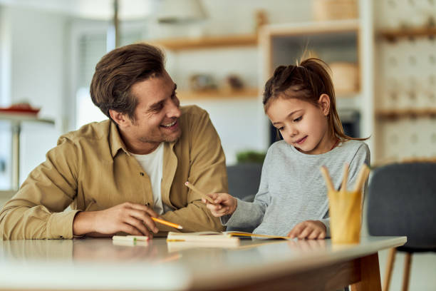 istock Smiling father looking at his daughter while she's drawing with crayons. 1691994670