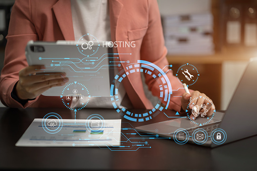 Woman using computer, tablet and presses his finger on the virtual screen inscription Hosting on desk, Web hosting concept, Internet, business, digital technology concept.