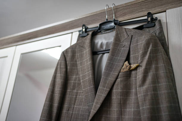 A stylish gray men's suit hangs on a hanger in the room.