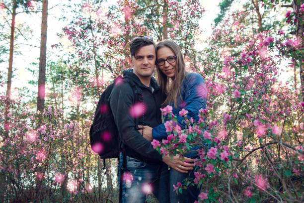 Portrait of young beauty woman in purple rhododendron flowers. Blooming rhododendron - maralnik in Altai mountain forest in the spring.