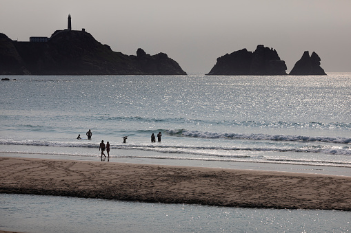 View of the Cavo Vilán lighthouse from Balea beach with bathers. Costa da morte. Camariñas
