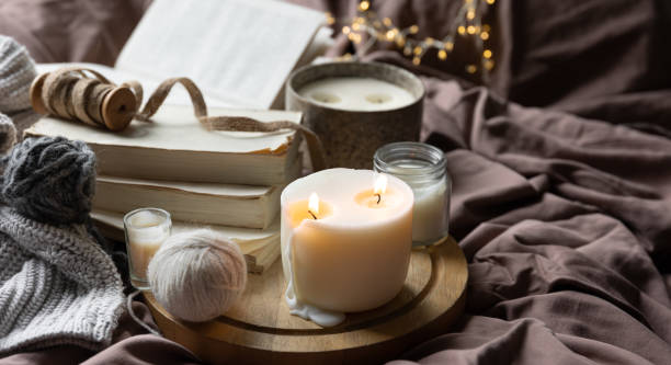 istock Cozy home composition with candles, books and knitted element in the bed. 1692023116