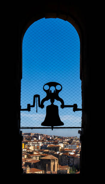 教会の塔からサラマンカの街の景色を望む古い大聖堂のブロンズベルの逆光のシルエット。反鳩メッシュで保護されています。 - church bell tower temple catholicism ストックフォトと画像
