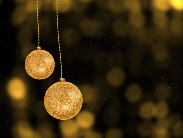 two golden glitter christmas balls hänging , dark background with lights