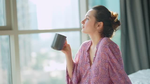 Woman looking at cityscape and having her morning cup of coffee