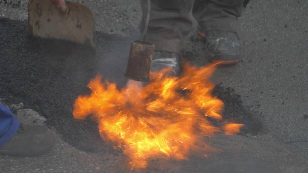 istock Utility Workers Fixing Gap in a Road by FIlling it with Hot Asphalt 1692069317