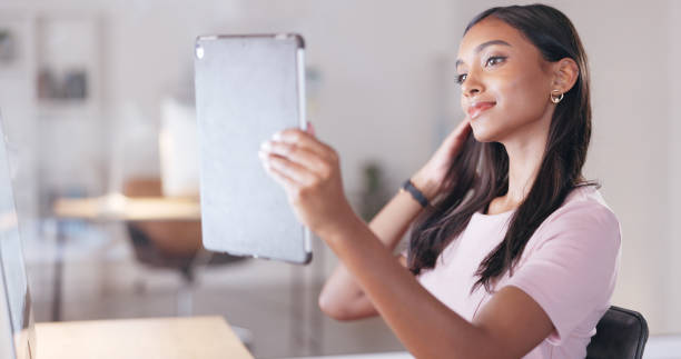 istock Young happy woman taking a selfie with a digital tablet while relaxing in an office at work. One smiling female student taking pictures to post on social media while sitting alone in a library 1692083785