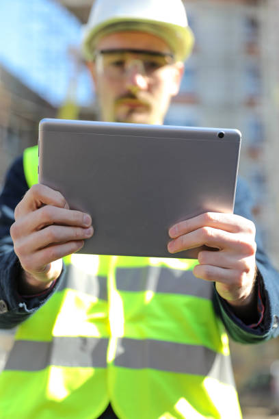 istock Male architect using digital tablet at construction site, he wears a protective vest and helmet 1692086143