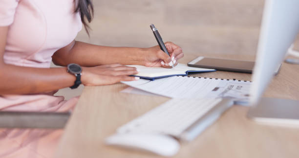 istock Office woman working on a schedule or online appointments and making notes in her calendar diary. One young professional therapist planning, checking and filing information on desktop computer 1692089560