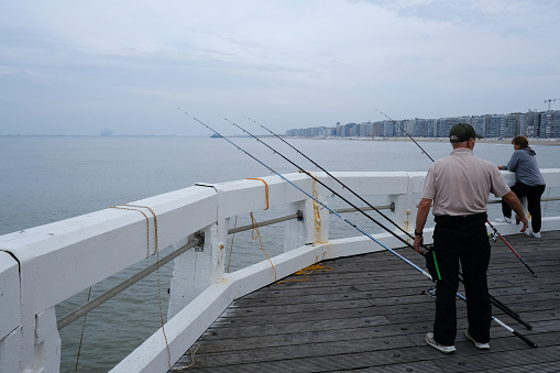 People fishing with fish stick in promenade of De Haan, Belgium on September 17, 2023.