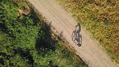 Aerial of Woman Riding a Bicycle Alone on Dirt Road by Field of Grain