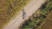 Aerial of Woman Riding a Bicycle Alone on Dirt Road by Field of Grain