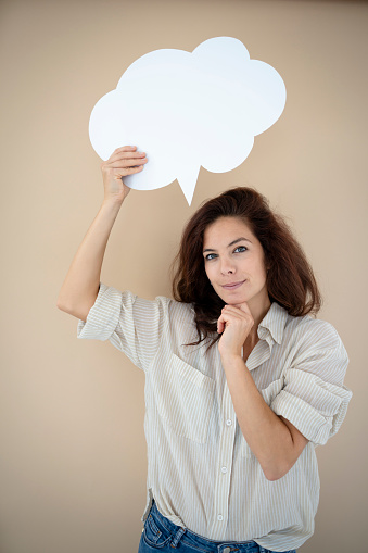 beautiful woman holding white speech bubble in front of brown background