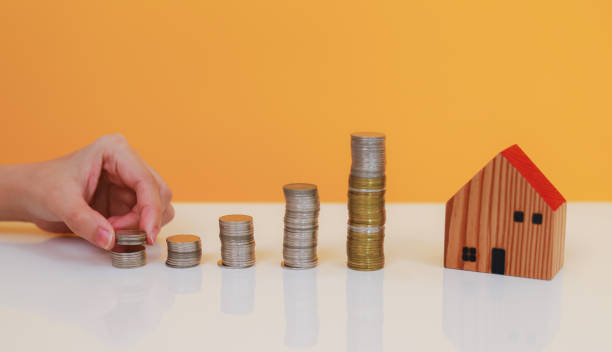 istock Asian woman putting coin increase on coins stacking with house model while preparation to saving for property investment and house mortgage. Home purchase mortgage, saving money and financial concept. 1692113123