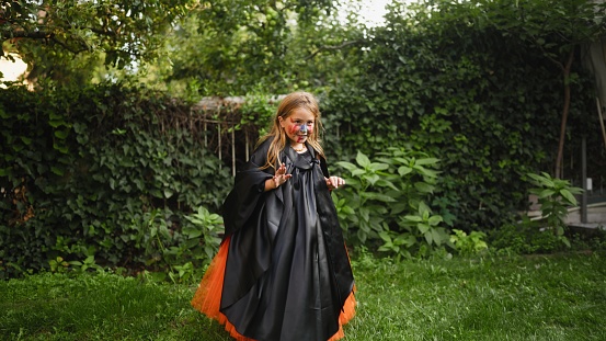A portrait of a small girl in a Halloween costume in back yard at home.